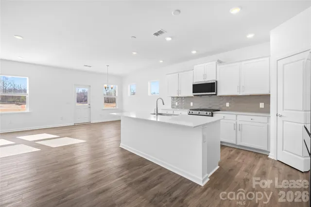 a view of a room with wooden floor ceiling fan and window