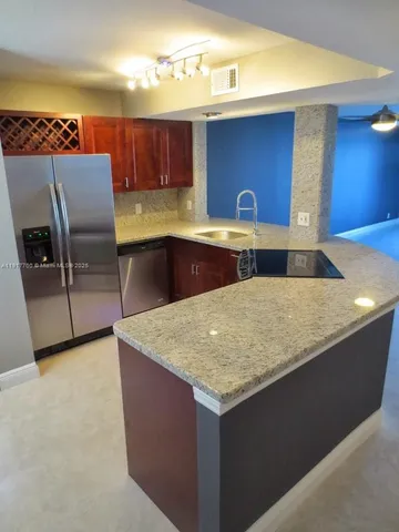 a kitchen with granite countertop a sink a stove and a wooden cabinets