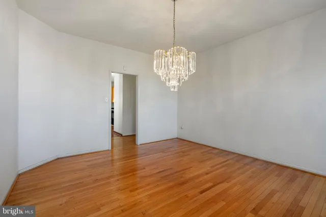 a view of an empty room with wooden floor and chandelier