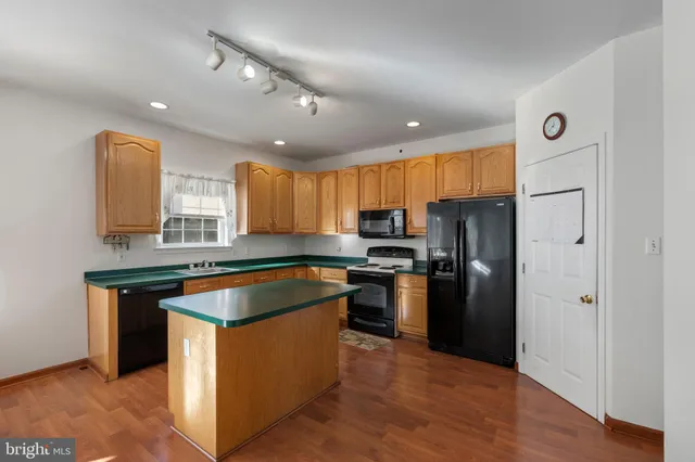 a kitchen with stainless steel appliances granite countertop a refrigerator a sink a stove a microwave and island with wooden floor