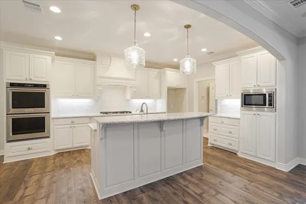 a kitchen with white cabinets stainless steel appliances and wooden floor