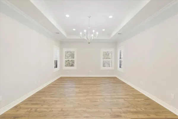 an empty room with chandelier fan and windows