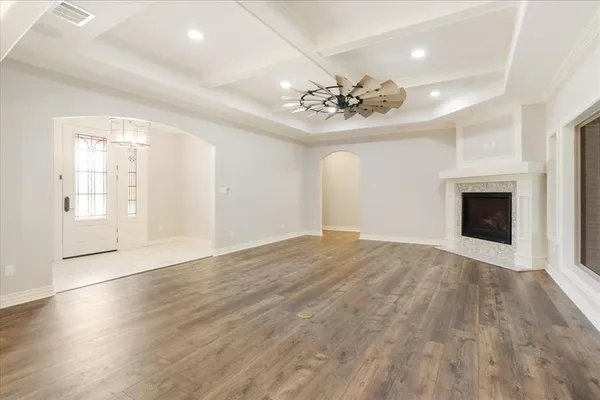 an empty room with wooden floor fireplace and chandelier