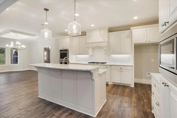 a large kitchen with granite countertop a white stove top oven and white cabinets