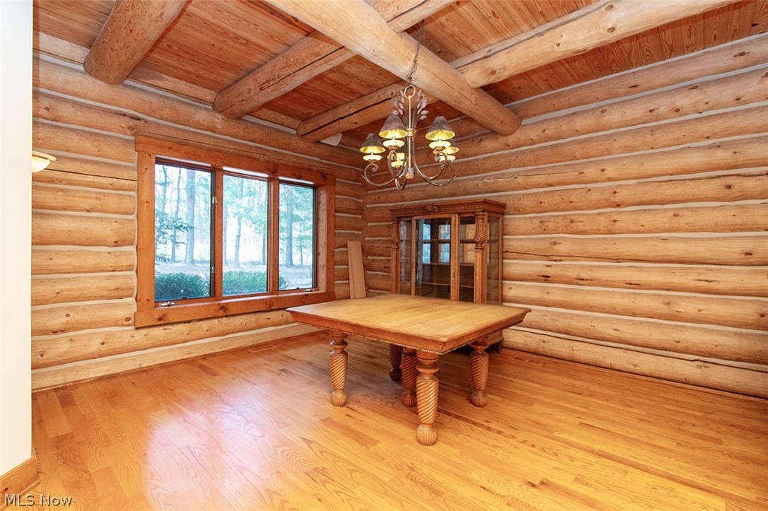 1871 Mattingly Road Hinckley, OH 44233 - Photo 16 of 50 Unfurnished dining area with a chandelier, wood finished floors, log walls, and a wood ceiling with exposed beams