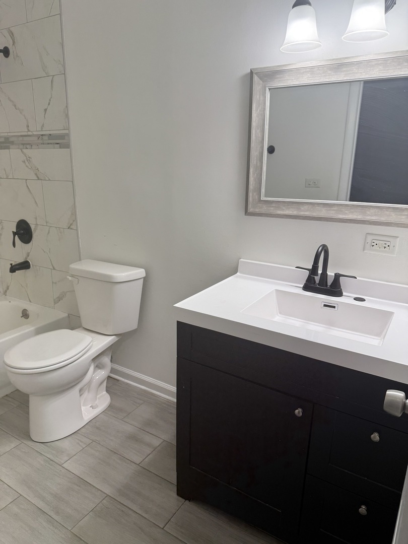 1319 Kingsbury Drive, Unit 2 Hanover Park, IL 60133 - Photo 29 of 44 a bathroom with a toilet a sink and mirror