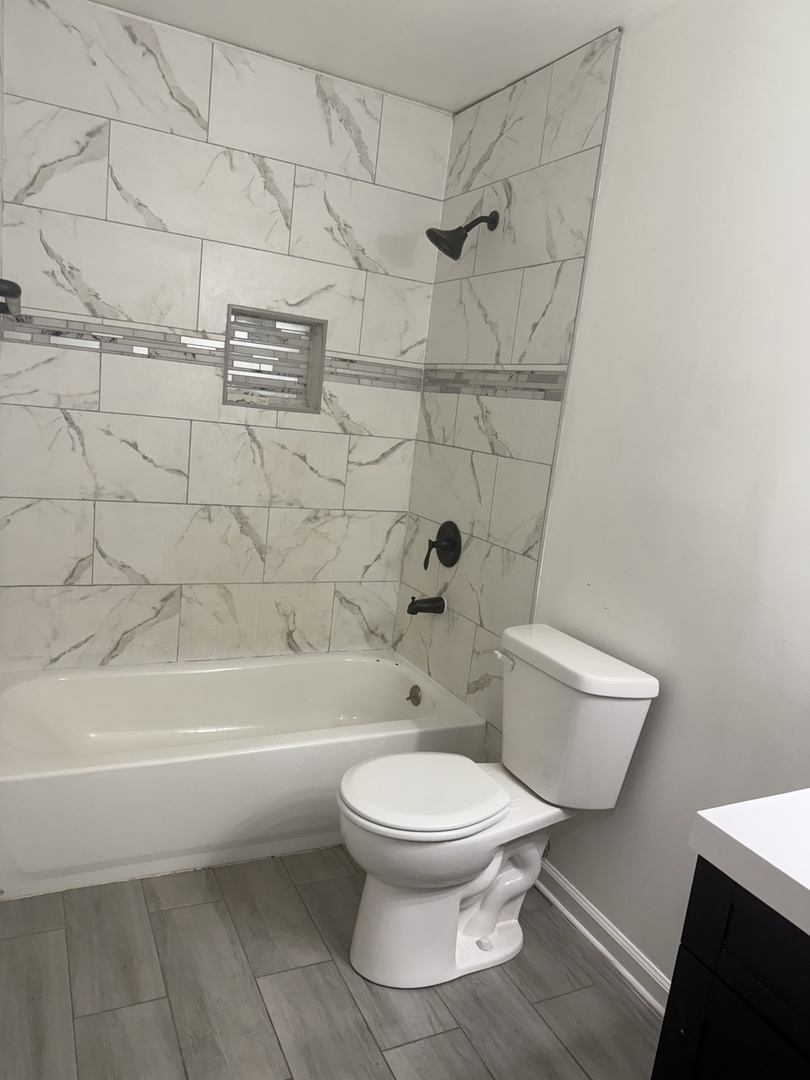 1319 Kingsbury Drive, Unit 2 Hanover Park, IL 60133 - Photo 32 of 44 a white toilet and tub sitting next to a bathroom sink