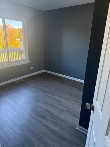an empty room with wooden floor and a window