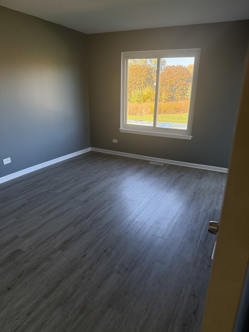 1319 Kingsbury Drive, Unit 2 Hanover Park, IL 60133 - Photo 36 of 44 an empty room with wooden floor and a window