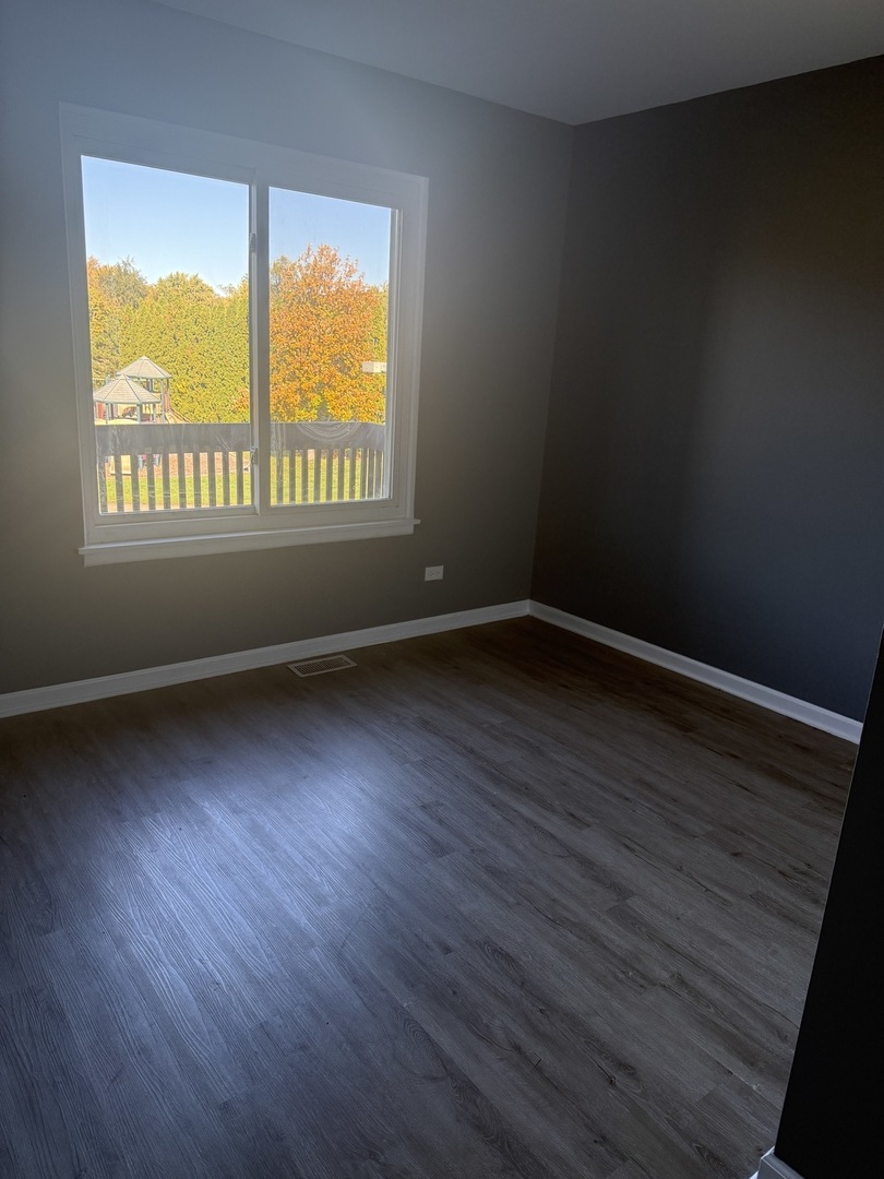 1319 Kingsbury Drive, Unit 2 Hanover Park, IL 60133 - Photo 43 of 44 a view of an empty room with wooden floor and a window