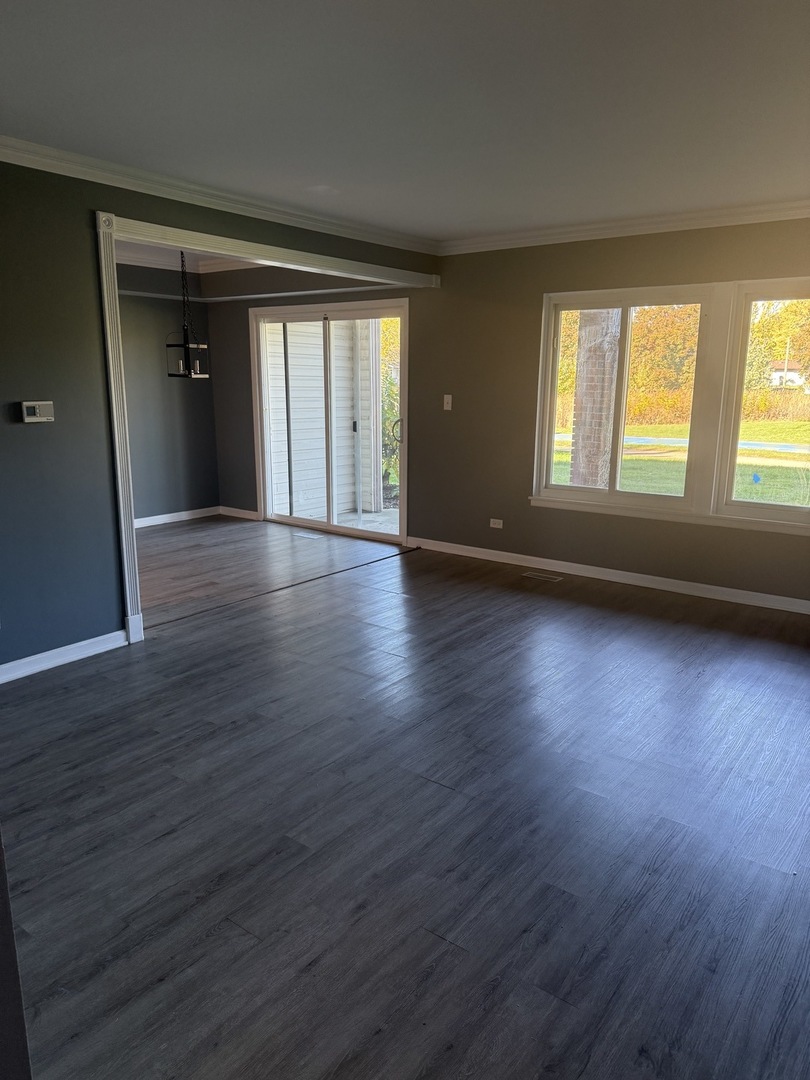 1319 Kingsbury Drive, Unit 2 Hanover Park, IL 60133 - Photo 6 of 44 a view of an empty room with wooden floor and a window