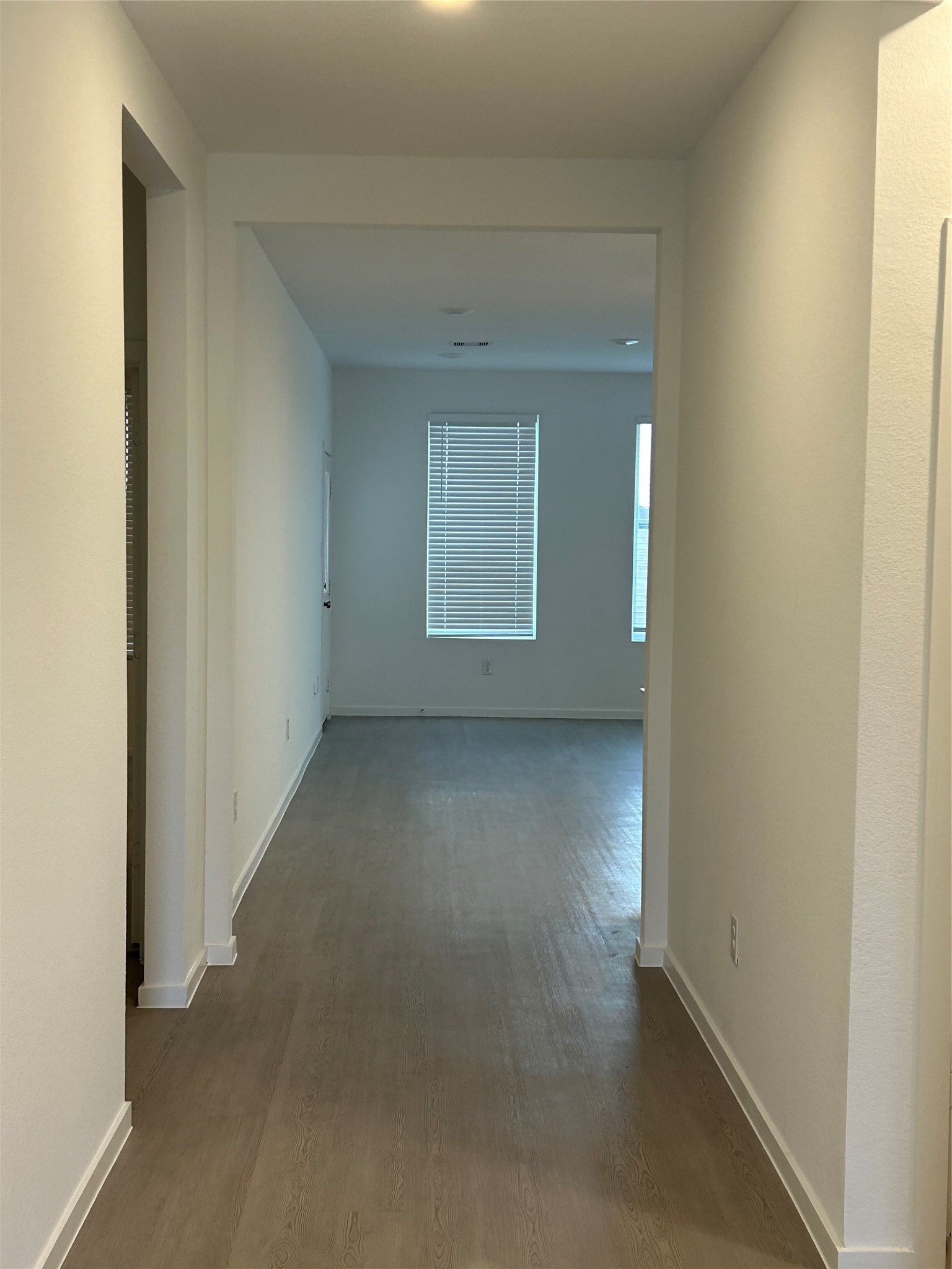 26419 Virginia Wild Rye Lane Katy, TX 77493 - Photo 7 of 31 This photo shows a bright, modern hallway with light wood flooring and white walls, leading to a room with large windows.