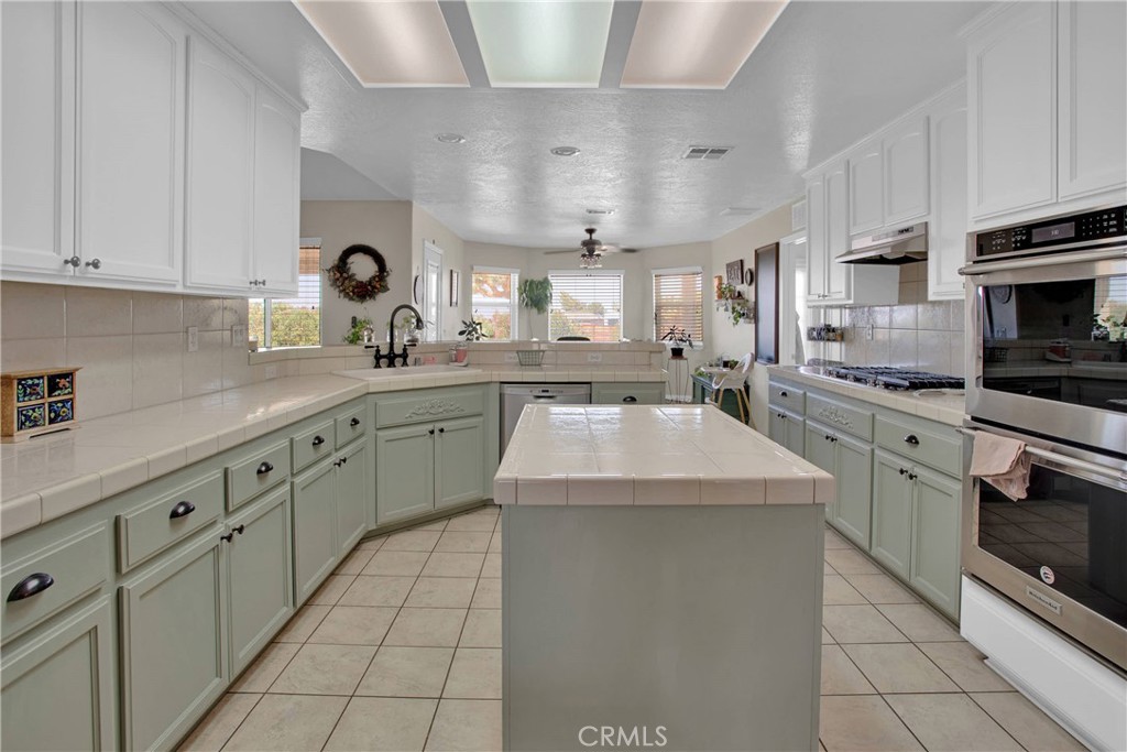 7330 Smoke Tree Road Phelan, CA 92371 - Photo 17 of 46 a kitchen with kitchen island granite countertop white cabinets white stainless steel appliances with a sink and dishwasher