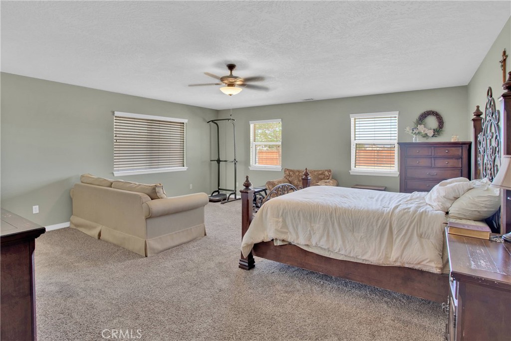 7330 Smoke Tree Road Phelan, CA 92371 - Photo 23 of 46 a spacious bedroom with a bed couch and window