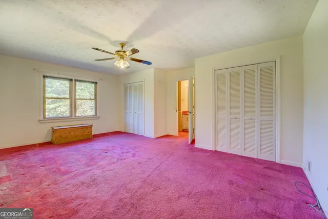 an empty room with windows and ceiling fan