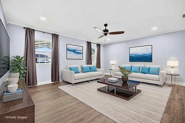 a view of an empty room with wooden floor and a ceiling fan