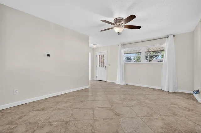 a view of an empty room with wooden floor and a ceiling fan