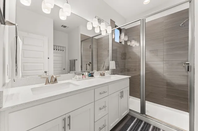 a bathroom with a double vanity sink mirror and shower