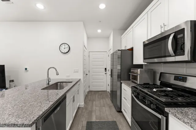 a kitchen with stainless steel appliances granite countertop a sink stove and refrigerator