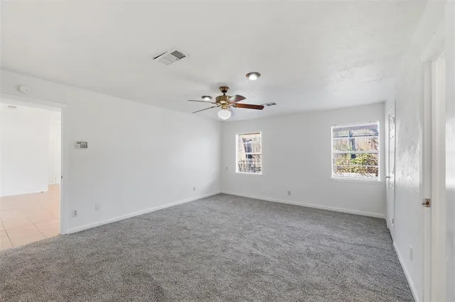an empty room with windows and chandelier fan