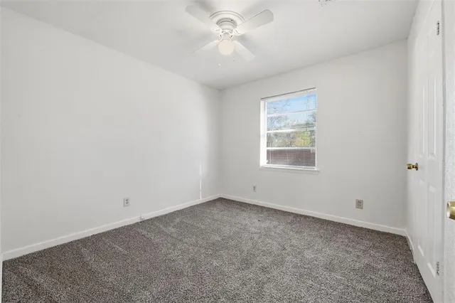 an empty room with a window and a ceiling fan