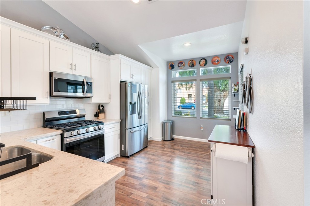 705 Fuchsia Lane Perris, CA 92571 - Photo 8 of 29 a kitchen with stainless steel appliances a stove a refrigerator a sink a stove and white cabinets with wooden floor