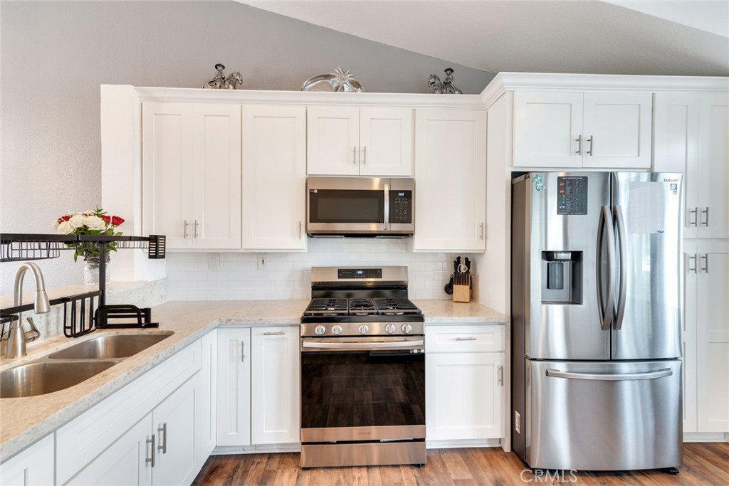 705 Fuchsia Lane Perris, CA 92571 - Photo 10 of 29 a kitchen with white cabinets and stainless steel appliances