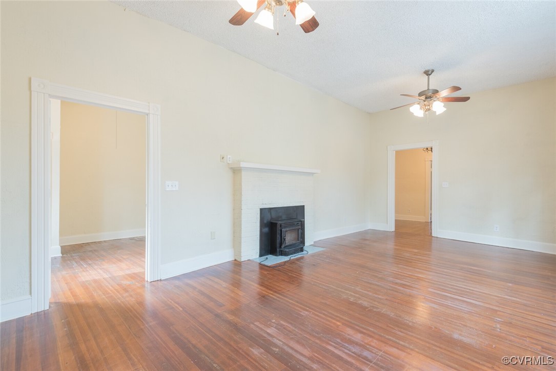 7808 Wells Road Ford, VA 23850 - Photo 8 of 41 an empty room with wooden floor a chandelier fan and a fireplace