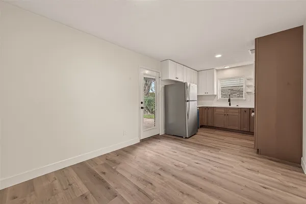 a view of a kitchen with refrigerator and wooden floor
