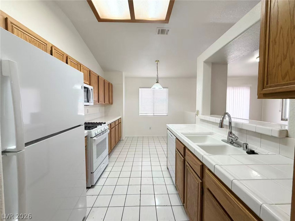 8620 Magnolia Ridge Avenue Las Vegas, NV 89134 - Photo 5 of 15 White tiled floors lead into a kitchen boasting an eat-in area and a convenient breakfast bar.