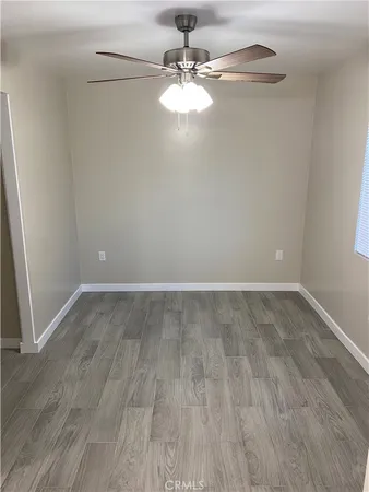 a view of a room with wooden floor and a ceiling fan