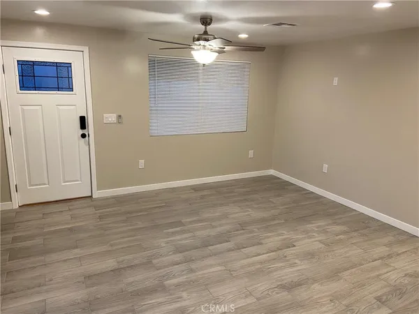 a view of an empty room with window and wooden floor