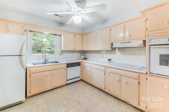a kitchen with granite countertop white cabinets white appliances a sink and a window