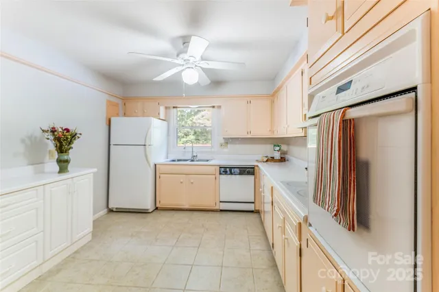 a kitchen with a refrigerator a sink and dishwasher with white cabinets