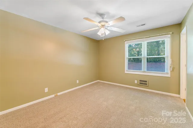 an empty room with a window and a ceiling fan
