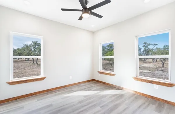 a view of an empty room with a window and wooden floor
