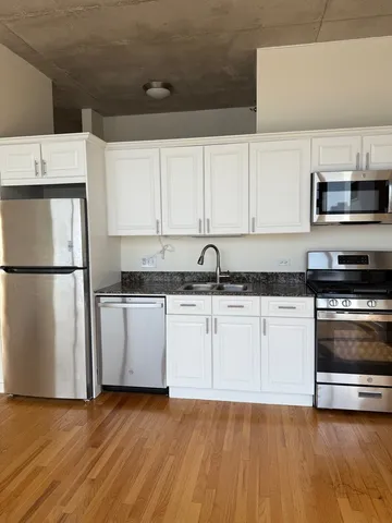 a kitchen with granite countertop a refrigerator and a stove top oven