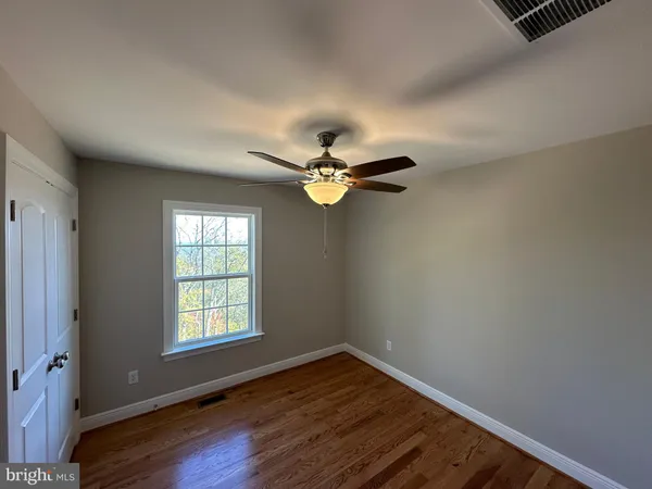 an empty room with wooden floor fan and windows