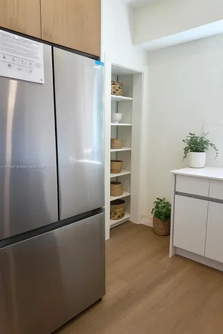 a view of a refrigerator in kitchen and an empty room