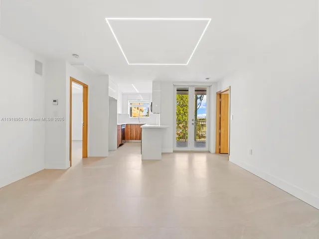 a view of an empty room with a window and kitchen view