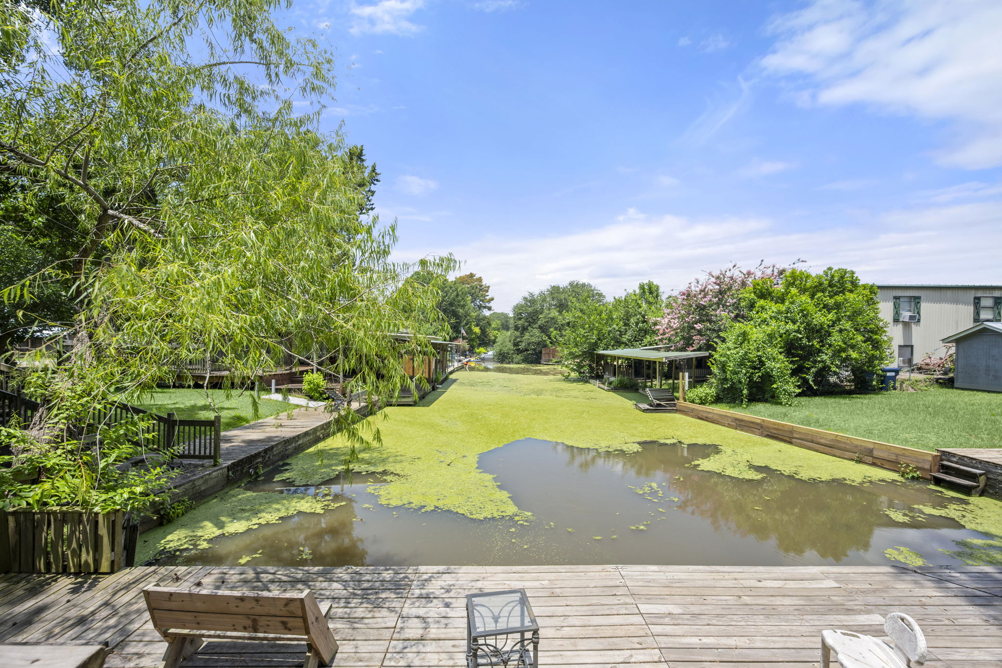 9649 Warm Spring Willis, TX 77318 - Photo 14 of 30 A tranquil waterside retreat awaits, featuring a spacious wooden deck for relaxing and enjoying the views.