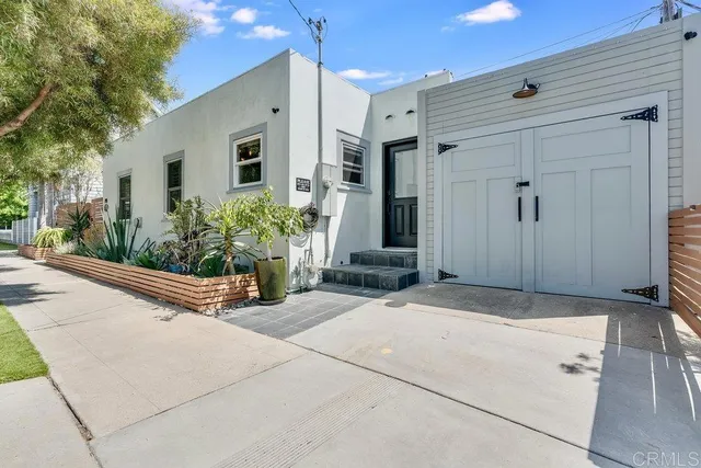 a view of a house with potted plants and a garage