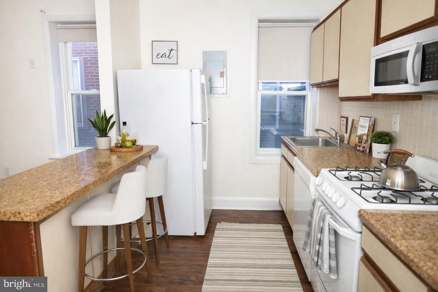 2309 East York Street, Unit 2R Philadelphia, PA 19125 - Photo 3 of 8 a kitchen with stainless steel appliances granite countertop a table chairs and a refrigerator
