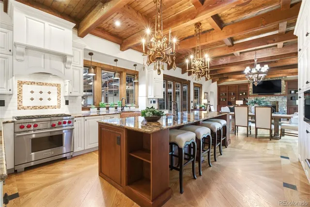 a large kitchen with stainless steel appliances granite countertop a stove and a view of living room