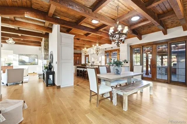 a dining room with wooden floor a chandelier a glass table and chairs