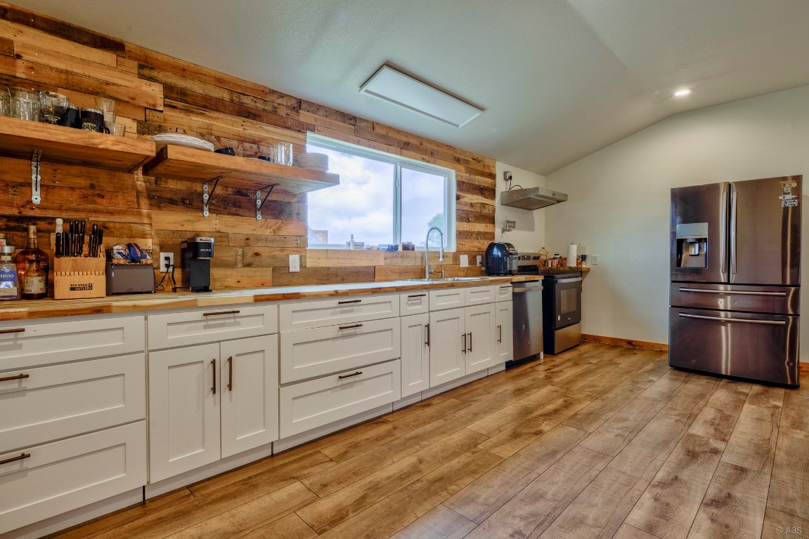 135 Wilbarger Bend Road Bastrop, TX 78602 - Photo 20 of 37 Kitchen with lofted ceiling, stainless steel appliances, open shelves, and white cabinets