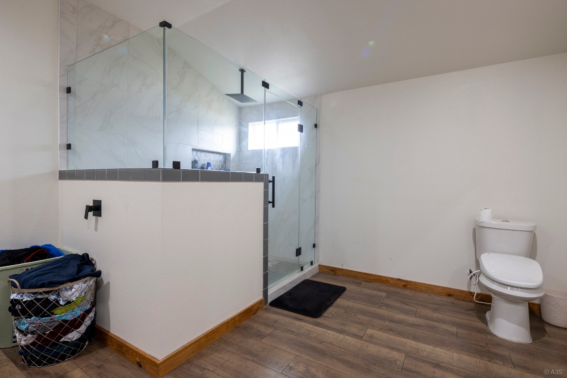 135 Wilbarger Bend Road Bastrop, TX 78602 - Photo 25 of 37 Bathroom featuring toilet, a marble finish shower, wood finished floors, and baseboards