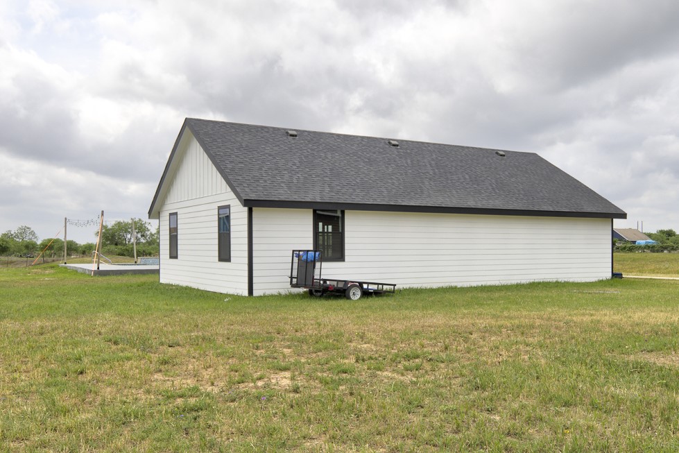 135 Wilbarger Bend Road Bastrop, TX 78602 - Photo 32 of 37 Back of property with roof with shingles and a lawn