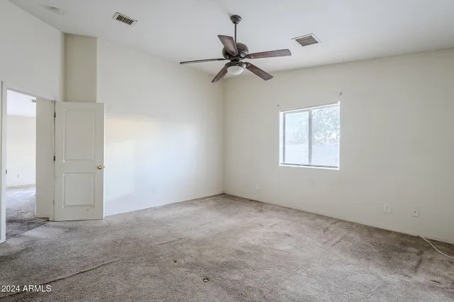 an empty room with windows and fan