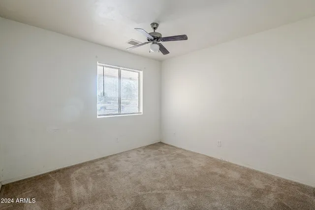 an empty room with a window and a fan